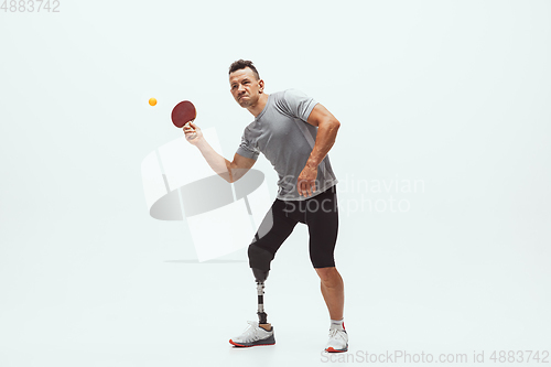 Image of Athlete with disabilities or amputee isolated on white studio background. Professional male table tennis player with leg prosthesis training and practicing in studio.