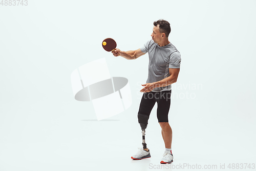 Image of Athlete with disabilities or amputee isolated on white studio background. Professional male table tennis player with leg prosthesis training and practicing in studio.