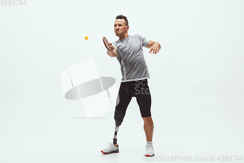 Image of Athlete with disabilities or amputee isolated on white studio background. Professional male table tennis player with leg prosthesis training and practicing in studio.