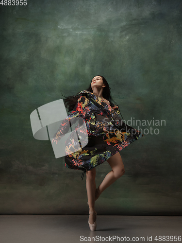 Image of Young graceful tender ballerina on dark green studio background