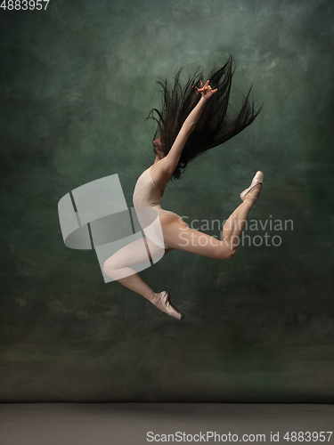 Image of Young graceful tender ballerina on dark green studio background