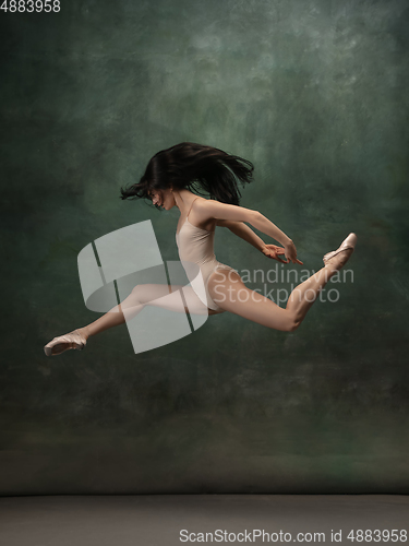 Image of Young graceful tender ballerina on dark green studio background