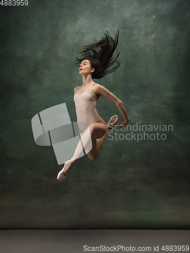 Image of Young graceful tender ballerina on dark green studio background