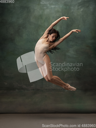 Image of Young graceful tender ballerina on dark green studio background
