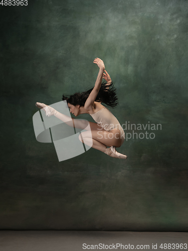 Image of Young graceful tender ballerina on dark green studio background