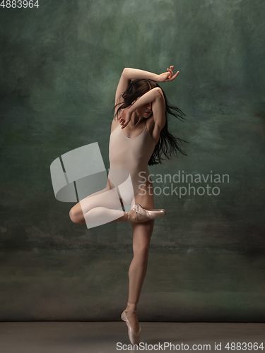 Image of Young graceful tender ballerina on dark green studio background