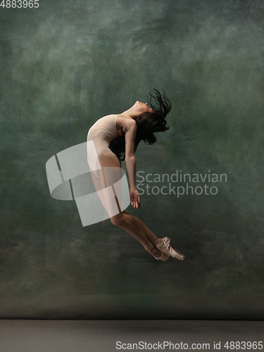 Image of Young graceful tender ballerina on dark green studio background