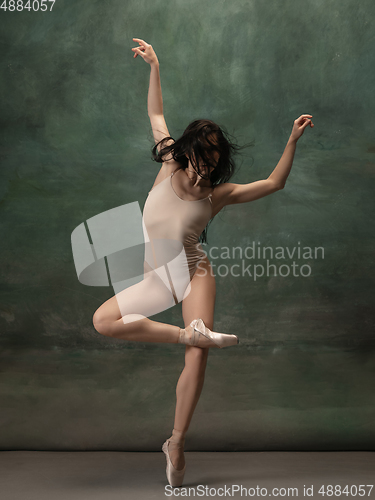 Image of Young graceful tender ballerina on dark green studio background