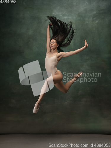 Image of Young graceful tender ballerina on dark green studio background