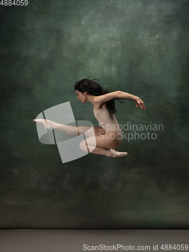 Image of Young graceful tender ballerina on dark green studio background