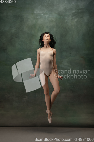 Image of Young graceful tender ballerina on dark green studio background