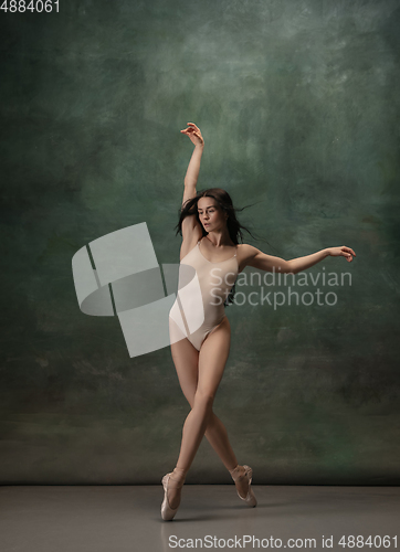 Image of Young graceful tender ballerina on dark green studio background