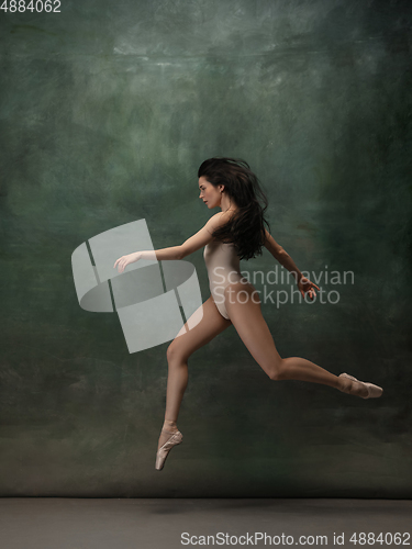 Image of Young graceful tender ballerina on dark green studio background