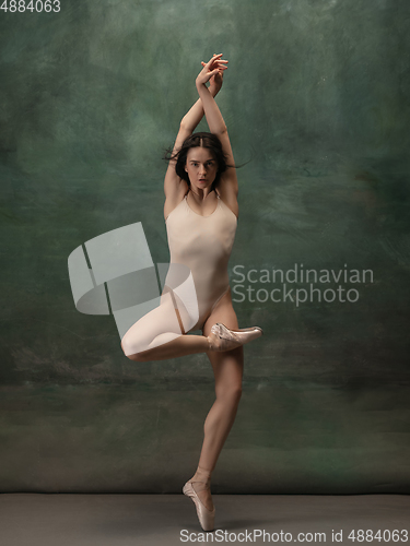 Image of Young graceful tender ballerina on dark green studio background