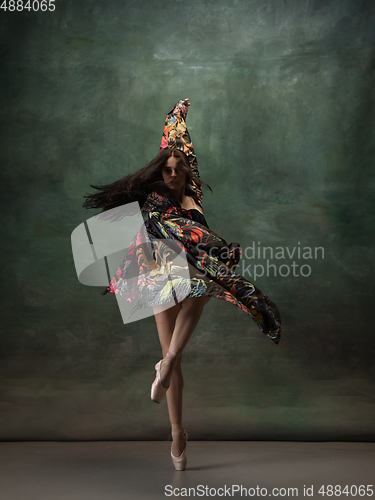 Image of Young graceful tender ballerina on dark green studio background