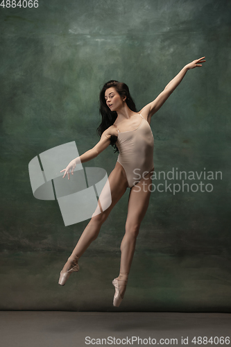 Image of Young graceful tender ballerina on dark green studio background