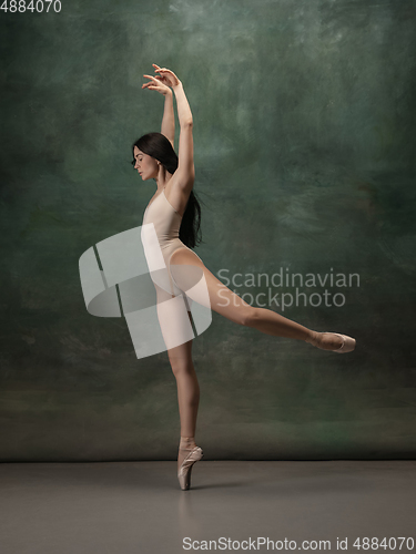 Image of Young graceful tender ballerina on dark green studio background