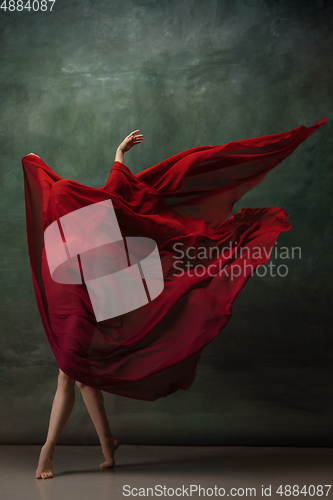 Image of Young graceful tender ballerina on dark green studio background