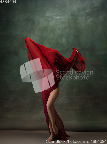 Image of Young graceful tender ballerina on dark green studio background
