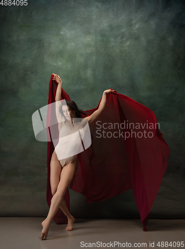 Image of Young graceful tender ballerina on dark green studio background