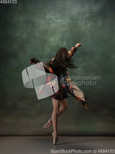 Image of Young graceful tender ballerina on dark green studio background