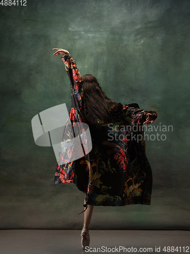 Image of Young graceful tender ballerina on dark green studio background