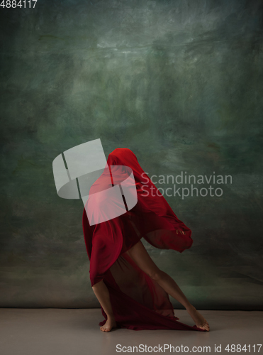 Image of Young graceful tender ballerina on dark green studio background