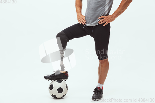 Image of Athlete with disabilities or amputee isolated on white studio background. Professional male football player with leg prosthesis training and practicing in studio.