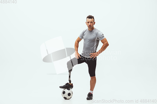 Image of Athlete with disabilities or amputee isolated on white studio background. Professional male football player with leg prosthesis training and practicing in studio.