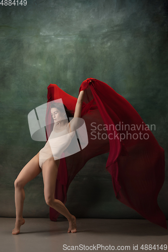 Image of Young graceful tender ballerina on dark green studio background