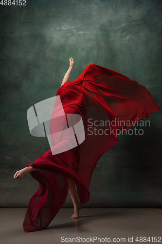 Image of Young graceful tender ballerina on dark green studio background