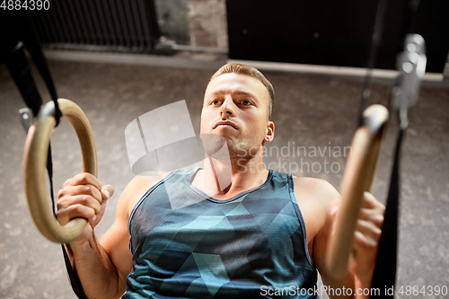 Image of man doing exercising on gymnastic rings in gym