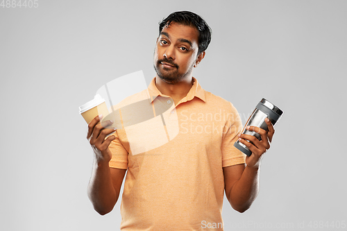 Image of man comparing thermo cup or tumbler and coffee cup