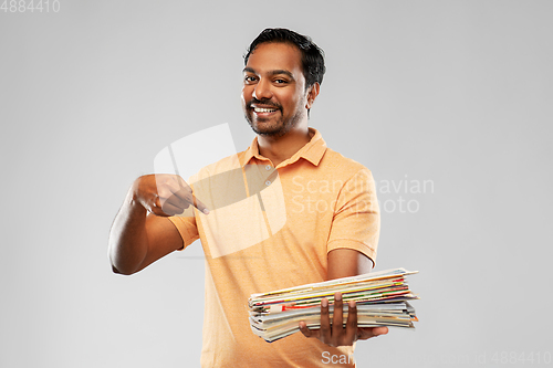 Image of smiling young indian man sorting paper waste