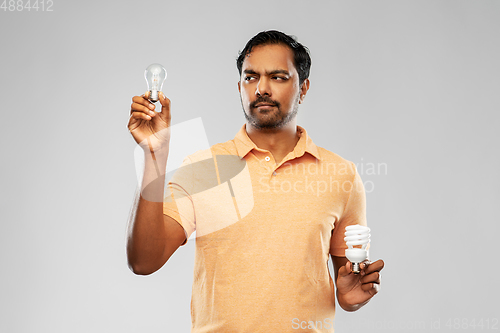 Image of indian man comparing different light bulbs