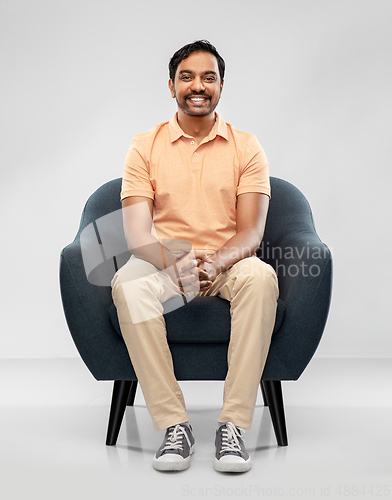 Image of happy smiling young indian man sitting in chair