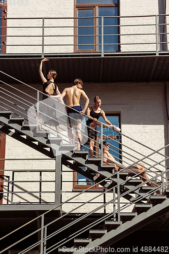 Image of The group of modern ballet dancers performing on the stairs at the city