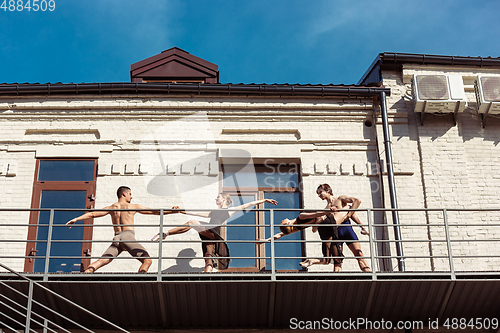 Image of The group of modern ballet dancers performing on the stairs at the city