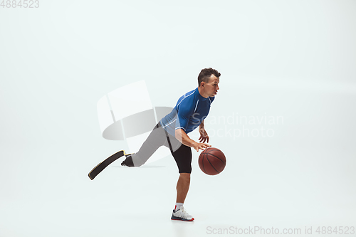 Image of Athlete with disabilities or amputee isolated on white studio background. Professional male basketball player with leg prosthesis training and practicing in studio.