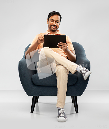 Image of happy indian man with tablet pc computer in chair