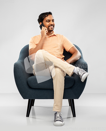 Image of happy indian man calling on smartphone in chair