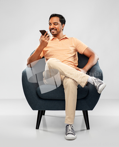 Image of happy indian man calling on smartphone in chair