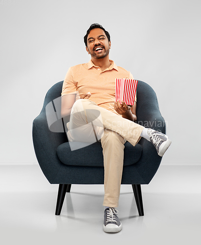 Image of happy smiling indian man eating popcorn in chair