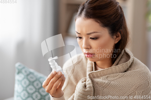 Image of sick asian woman with oral spray medicine at home
