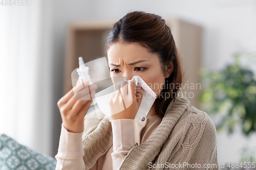 Image of sick asian woman with nasal spray medicine at home