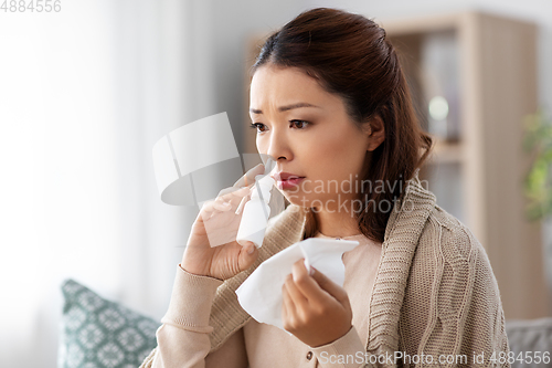Image of sick asian woman with nasal spray medicine at home