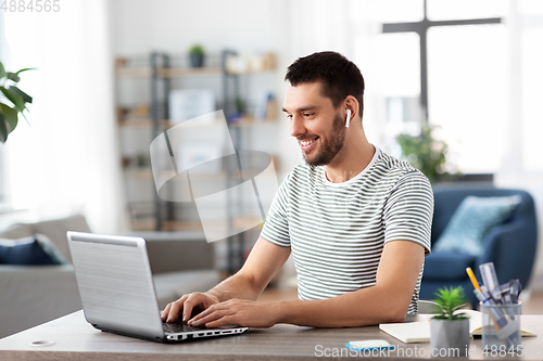 Image of man with laptop and earphones at home office