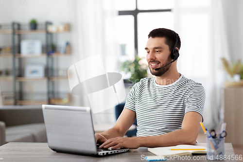 Image of man with headset and laptop working at home