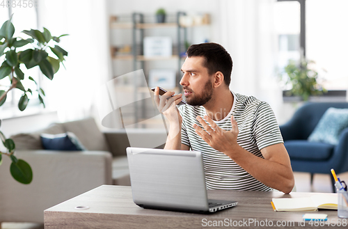 Image of man with laptop calling on phone at home office