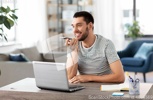 Image of man with laptop calling on phone at home office